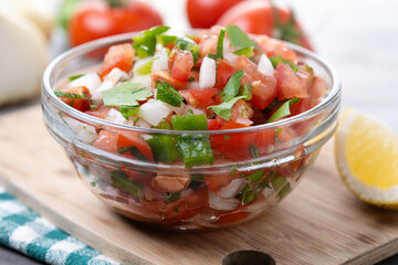 Traditional Mexican Pico de Gallo sauce in bowl on wooden table