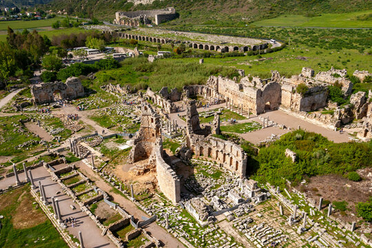 Aerial view of ancient ruins and stone columns in a scenic landscape, Perge, Turkey.
