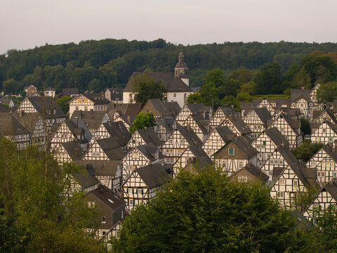 Aerial view of picturesque half-timbered houses and a charming church in a historic village surrounded by forest, Freudenberg, Germany.