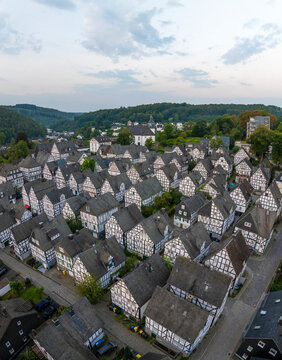 Aerial view of picturesque half-timbered houses in a charming village surrounded by hills and trees, Freudenberg, Germany.