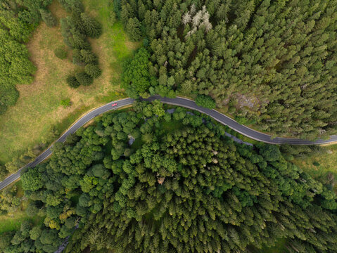 Aerial view of winding road through lush forest with car driving, Nova Ves, Czech Republic.
