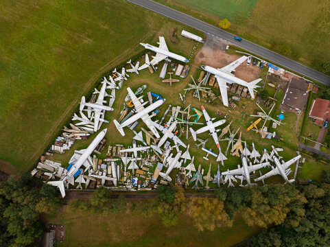 Aerial view of abandoned airplanes and helicopters in a rusty graveyard surrounded by trees and fields, Zruc Senec, Czech Republic.