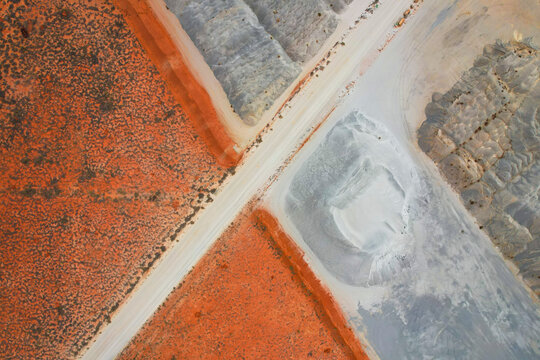 Aerial view of beautiful abstract patterns of red earth and barren landscape with a road and quarry, Pilbara Region, Australia.