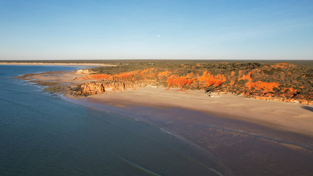 Aerial view of echo beach resort coastline with ochre cliff and the moon, Broome, Australia.
