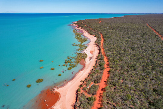 Aerial view of red sand beach and turquoise water with fishermen, Broome, Australia.