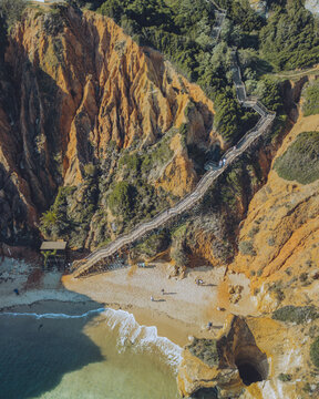 Aerial view of praia do camilo with a wooden staircase and scenic cliffs, lagos, portugal.