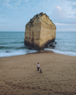 Aerial view of tranquil Praia da Cova Redonda with a scenic sea stack and sandy beach, Porches, Portugal.