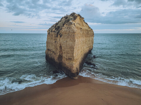 Aerial view of praia da cova redonda with beautiful sea stack and tranquil beach, Porches, Portugal.