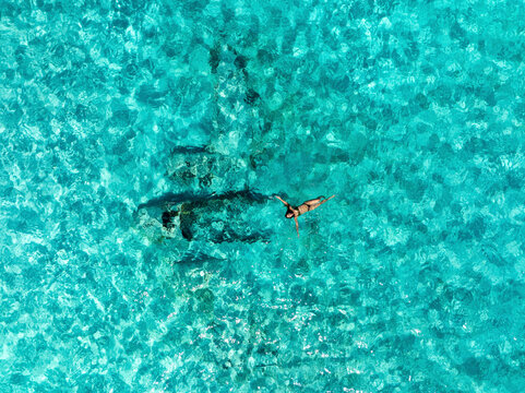 Aerial view of woman swimming in the turquoise ocean with crystal clear water, Exuma, The Bahamas.