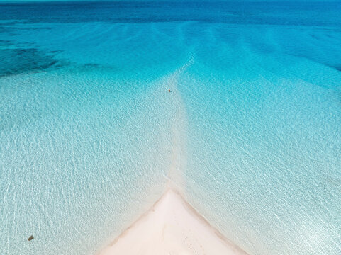 Aerial view of a serene woman in the turquoise sea near a beautiful sandbank, South Eleuthera, The Bahamas.
