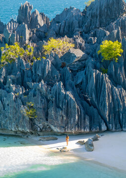 Aerial view of smith point beach with a woman on the beautiful white sand and turquoise water, Banuang Daan, Coron, Palawan, Philippines.