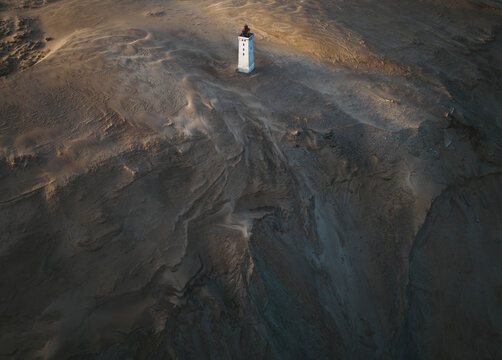 Aerial view of a beautiful lighthouse on a deserted sandy landscape with vast barren terrain, Jutland, Denmark.