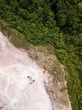 Aerial view of a quarry with heavy machinery amidst a forested landscape, Bila, Bosnia and Herzegovina.