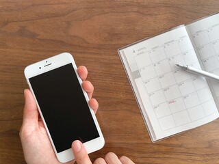 スマホを持つ手と4月のスケジュール帳
