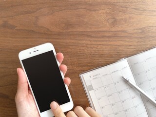 スマホを持つ手と3月のスケジュール帳