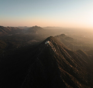 Aerial view of the majestic Shree Savitri Mata Temple on a mountain peak surrounded by a scenic valley at sunrise, Pushkar, Rajasthan, India.