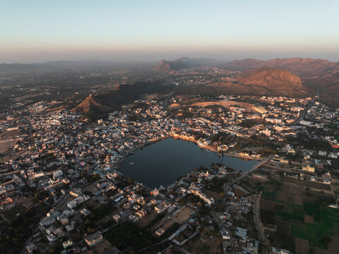 Aerial view of Pushkar Lake with scenic ghat and picturesque mountains at sunset, Pushkar, Rajasthan, India.