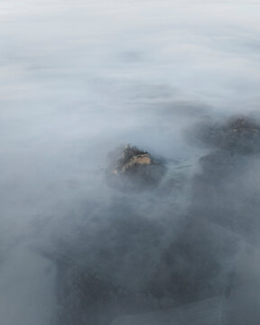 Aerial view of a serene and ethereal landscape shrouded in fog and mist at sunrise, Tuscany, Reggello, Italy.