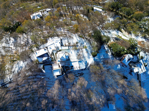 Aerial view of snow-covered trees and quaint buildings in a serene winter landscape, Bre sopra Lugano, Switzerland.