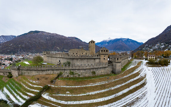 Aerial view of the historic Castle of Montebello surrounded by snowy mountains and picturesque vineyards, Bellinzona, Switzerland.
