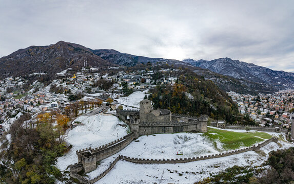 Aerial view of the historic Castle of Montebello surrounded by snow-capped mountains and a picturesque town, Bellinzona, Switzerland.