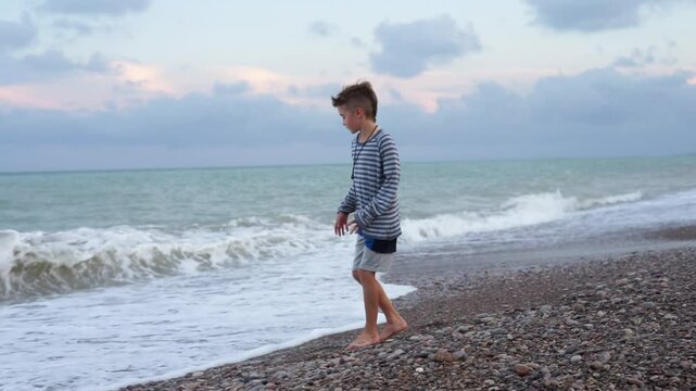 Boy throwing stone into ocean in slow motion