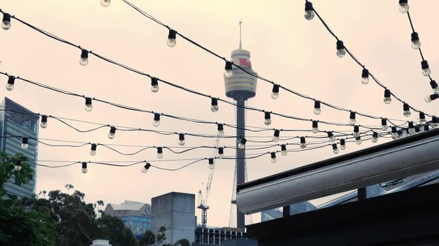 Hanging Lightbulbs With Sydney Centrepoint Tower In The Background In Australia. Low Angle Shot