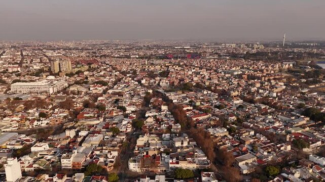 Aerial flyover Parque Chacabuco district in Buenos Aires City. Sunset time with Pedro Bidegain Stadium in distance. Aerial establishing wide shot.
