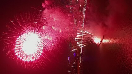 Vertical format: Fireworks explode over sea at Pattaya Beach, Thailand - Powered by Adobe