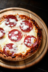 Pizza with salami and mozzarella cheese. Wooden background. Soft focus.