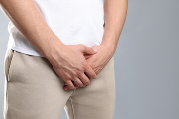 STD (sexually transmitted diseases). Man suffering from symptoms on grey background, closeup