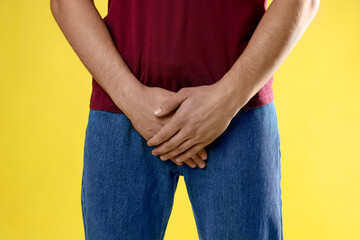 STD (sexually transmitted diseases). Man suffering from symptoms on yellow background, closeup