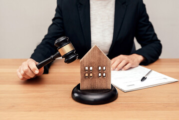 Close up of Judge holding gavel about to hit house model, real estate dispute concept