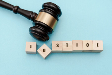 Judge gavel asserting justice with wooden cubes on blue background, legal system and court decisions