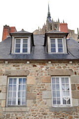 Fototapeta premium Mont-Saint-Michel= Le Montoise medieval building rear facade, seen under the abbey bell tower and spire from the rampart walkway. Normandy-France-167