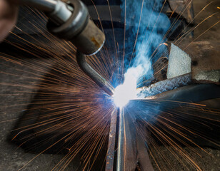 Welding process showcasing intense sparks and bright flames in a workshop setting during daytime