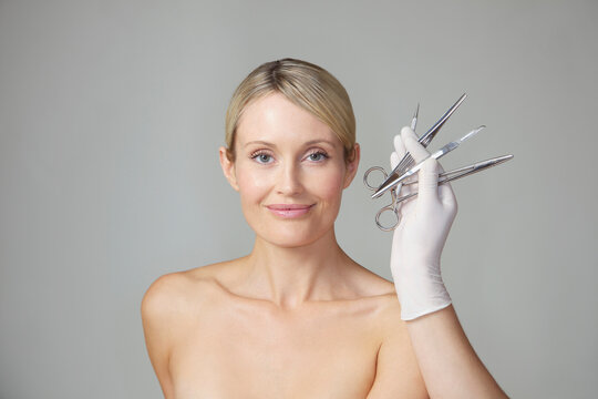 Doctor's Hand Holding Surgical Instruments in front of Woman's Face
