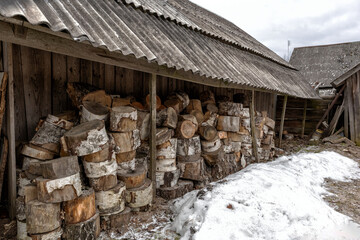 
A firewood shed with stacked bundles of firewood under the canopy.