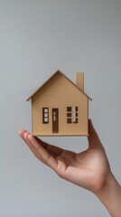 A woman's hand holding a small white model house.