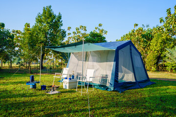Camping tents on green grass  in the morning, vintage cabin tents, antique gas lamps, retro chairs,...