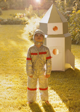 Boy Wearing Space Suit Standing in front of Cardboard Rocket Spacecraft
