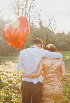 Couple in Park Holding Heart Shaped Balloon, Back View
