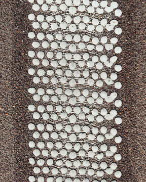 View from above textured white dots of road marking
