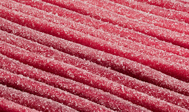 Full frame close up red strawberry fruit gum sour candy straws speckled with sugar crystals
