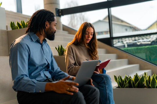Business colleagues collaborating on project using laptop and notebook in modern office space
