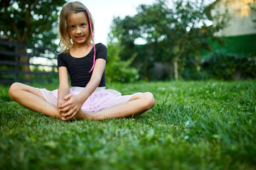 Young Girl Sitting Cross-legged on Lush Green Grass Enjoying a Sunny Day Outdoors