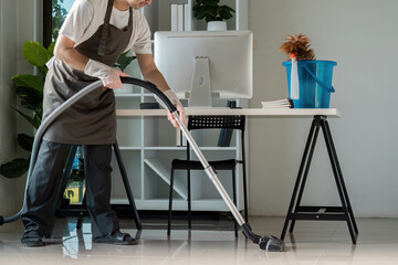 Professional Cleaner Vacuuming Modern Office Space with Desk and Computer in Bright, Tidy...