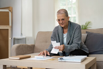 Obraz premium Senior Woman Planning Retirement Finances at Home with Documents and Calculator on Table