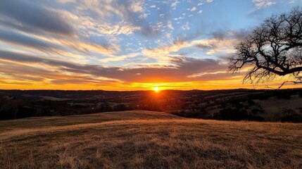 Fototapeta premium A sun setting behind rolling hills, with golden light bathing the landscape,