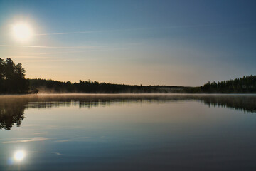Lake in Sweden, mirror-smooth water with romantic light and trees on the shore